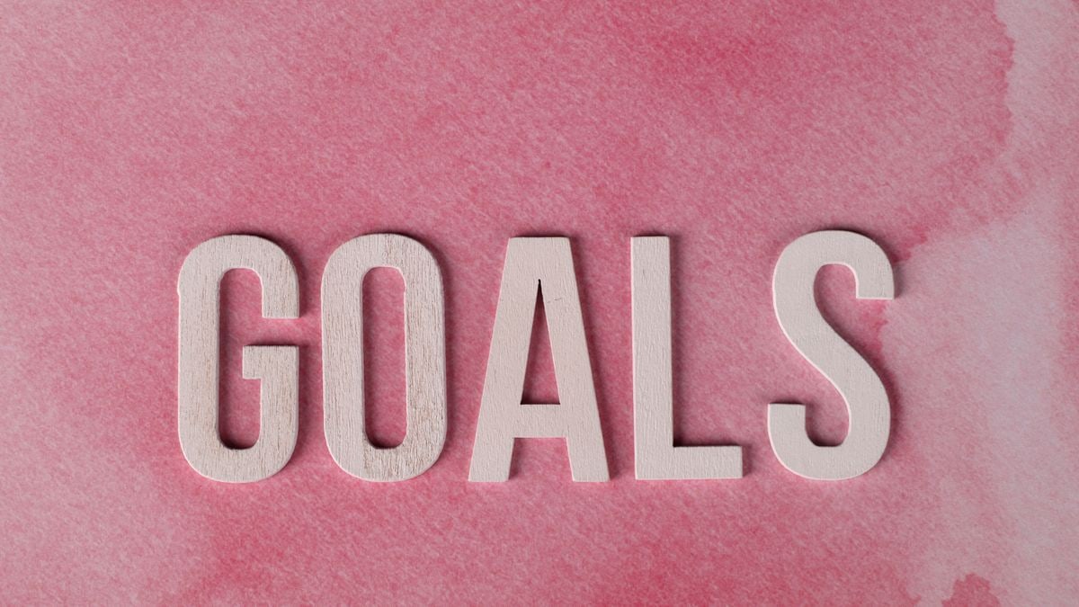 Motivational word 'GOALS' on a pink watercolor background for inspiration.